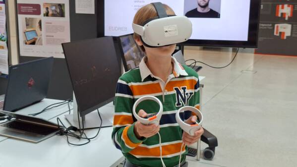 Ein Junge sieht sich in der Umgebung um, während er ein VR-Headset trägt und in beiden Händen Controller hält.